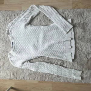 Vit kabelstickad tröja från H&M - Säljer en vit kabelstickad tröja från H&M i storlek S (36-38). Tröjan har lång ärm, rund halsringning och ribbade muddar. Perfekt för lager-på-lager och passar till många olika stilar.
