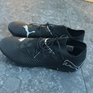 Svarta fotbollsskor från Puma - Säljer dessa Svarta fotbollsskor från Puma med vit logga på ovansidan och hälen. Skorna har snörning, stickad strumpkrage och mönstrad ovandel i syntetmaterial. Använda endast 2 gånger. Nypris: 1600 mitt pris: 1000 men priset är inte hugget i sten så kan gå lägre vid snabb affär 