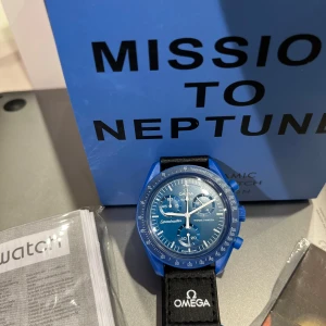Mission to neptune  - Säljer en blå Omega x Swatch Speedmaster MoonSwatch Mission to Neptune. Klockan har blå boett och blå urtavla med vita detaljer och svart textilband med Omega-logga. En sportig och unik klocka för dig som gillar cool design och rymdtema.