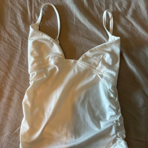Linne - Säljer denna jättesöta vita linne/topp i storlek xs. Säljs då den är lite för liten för mig. Väldigt stretchigt material☺️
