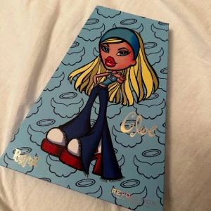 Bratz x Revolution Gloe ögonskuggspalett - Superfin ögonskuggspalett från Bratz x Revolution med 18 färger i både matta och skimrande nyanser. Paletten har blått fodral med Bratz-illustration och spegel.