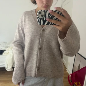 Beige stickad kofta med knappar - Mysig beige stickad kofta med v-ringning och tre stora knappar framtill. Storlek L men passar mig som har s