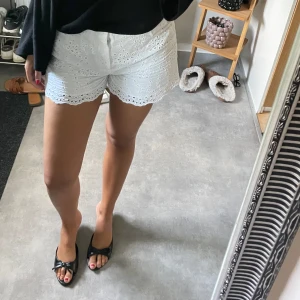 Vita broderade shorts med spetskant - Säljer ett par vita shorts med broderade detaljer. Shortsen passar för någon som har storlek S.