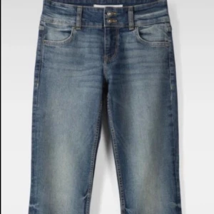 Blå bootcut jeans med dubbla knappar - Snygga blå bootcut jeans med dubbla knappar i midjan. Klassisk femficksmodell och skön passform. Perfekta till sneakers eller boots för en avslappnad look.