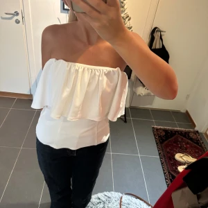 Vit bandeau tubtopp med volang - Aldrig andvänd! Passar mig som har xs/s i vanliga fall!                                                                            Säljer en superfin vit bandeau tubtopp med bred volang upptill. 