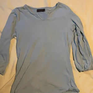 Ljusblå V-ringad topp från Vero Moda - Snygg ljusblå topp från Vero Moda med V-ringning och trekvartsärm. Enkel och stilren design som passar perfekt till jeans eller kjol. Mjuk och skön känsla, lätt att matcha med andra plagg.