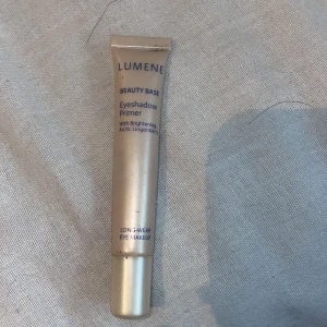 Lumene Beauty Base Eyeshadow Primer - Lumene Beauty Base Eyeshadow Primer i en smidig tub. Ljusbeige färg på förpackningen med blå text. Innehåller arktiskt lingonbär för extra lyster och är perfekt för att få ögonskuggan att sitta hela dagen. (Aldrig använt)
