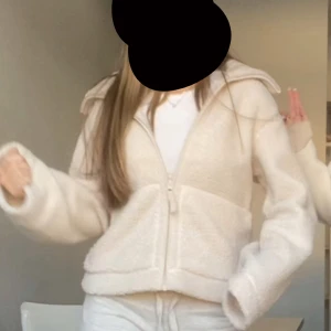 Beige teddyjacka med dragkedja - Mysig beige teddyjacka med dragkedja och stor krage. Jackan har en loose passform och är tillverkad i fluffigt teddy-material som ger en chill och trendig vibe. Perfekt att slänga på sig över en hoodie eller t-shirt för en avslappnad look.