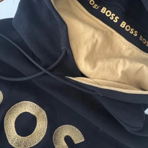 Svart hoodie från boss - Svart hoodie från boss med guld detaljer.