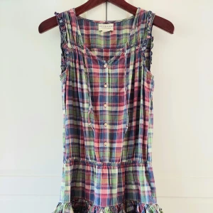 Rutig sommarklänning från Ralph Lauren - Superfin ärmlös kortklänning från Ralph Lauren i färgglatt rutigt mönster med blått, rött, grönt och vitt. Klänningen har knappar framtill, volangkant nertill och smockdetaljer vid axlarna. Perfekt för en avslappnad och cool sommarstil. Använd ett fåtal gånger! 