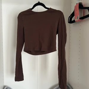 Brun croppad långärmad topp - En stilren brun croppad topp. Enkel och clean  som passar perfekt till jeans eller kjol. 