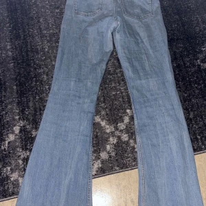 Ljusblå bootcut jeans - Säljer ett par ljusblå jeans med bootcut passform och klassiska fem fickor. Jeansen har hög midja och är tillverkade i denim. Perfekta för dig som gillar en retroinspirerad look.