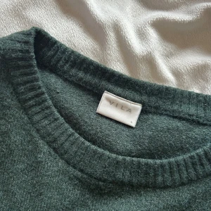 Mörkgrön stickad tröja från VILA - Mysig mörkgrön stickad tröja från VILA med rund halsringning och långa ärmar. Perfekt för mycket, klassisk och passar till det mesta. Använd fåtal gånger