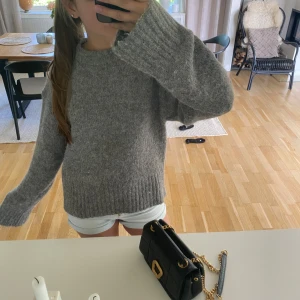 Grå stickad tröja - Mysig grå stickad tröja med lång ärm och bred ribbad kant nedtill och vid ärmslut. Perfekt för kyligare dagar och enkel att matcha med olika outfits. Säljer då den inte kommer till användning. Ändats använd en gång. Hör av er vid frågor😊
