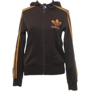 Vintage Adidas hoodie  - Vintage brun Adidas tröja med dragkedja och huva. Orangea ränder längs ärmarna och orange Adidas logga på bröstet. Trycket är lite slitet fram (se bild 4), annars bra skick! Storlek 40 men sitter mer som 36 🙌🏼