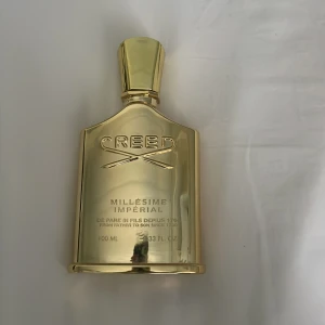 Creed Millésime Impérial Eau de Parfum 100ml - Lyxig parfym från Creed i en exklusiv guldfärgad flaska. Millésime Impérial är känd för sin fräscha och marina doftprofil med inslag av citrus och trä. Flaskan rymmer 100 ml och har en elegant, glänsande finish.