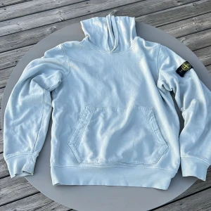Ljus vitt/grön hoodie från Stone Island - Säljer en ljus vitt/grön hoodie från Stone Island med klassisk logga på vänster ärm. Tröjan har stor magficka framtill och huva. Perfekt för dig som har avkopplande stil. Köpt på NK nypris 2400kr mitt pris 680kr men Pris går att diskutera. Passar ca 160 cm