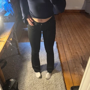 Svarta bootcut jeans - Säljer ett par svarta jeans med normal passform och bootcut form. Klassisk femficksmodell med knapp och dragkedja i gylfen. Perfekta till vardags och lätta att matcha med olika toppar. Jag har även öppnat upp sömmen längst ned på jeansen. Storlek S/32