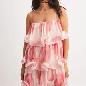 Rosa blommig volangklänning med tunna axelband - Supersöt kort klänning från nakd, perfekt till skolavslutning eller sommarens andra festligheter! Nyskick med prislappen kvar, endast testad. Säljer då den va för stor på mig som vanligtvis har xs i liknande kläder, skriv för fler bilder eller vid frågor🩷🩷🌸