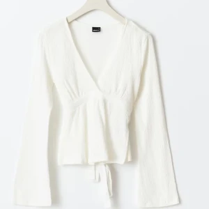 Vit topp med knytband - Snygg vit omlottopp med v-ringning och långa ärmar. Toppen har knytband i midjan som ger en fin passform. Perfekt att styla med jeans eller kjol. Använd en gång 💕