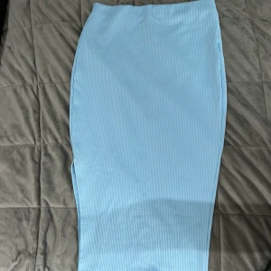 Ljusblå ribbad långkjol - Säljer en ljusblå långkjol med ribbad struktur. Kjolen har en rak och tight passform som sitter snyggt längs kroppen. Perfekt att styla med en enkel topp eller hoodie.