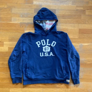 Sällsynt Ralph lauren hoodie - Mörkblå hoodie från Polo Ralph Lauren med vit text 'POLO 67 U.S.A.' på bröstet. Huvan är fodrad med tyg i amerikanska flaggans färger och mönster. Perfekt för en avslappnad och streetwear stilen. Riktigt fet och unik !  Strl m - s