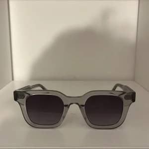 Grå transparenta solglasögon från CHIMI - Snygga solglasögon från CHIMI i transparent grå plast med fyrkantiga bågar och mörka glas. Perfekt accessoar för en stilren look. Kommer med originalfodral. Knappt använda