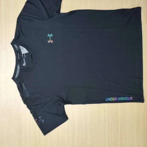 Svart t-shirt från Under Armour och svarta shorts - Säljer en svart t-shirt från Under Armour med logga i regnbågsfärger på bröstet och texten UNDER ARMOUR nere vid fållen. Perfekt för träning eller vardag, klassisk passform och korta ärmar.