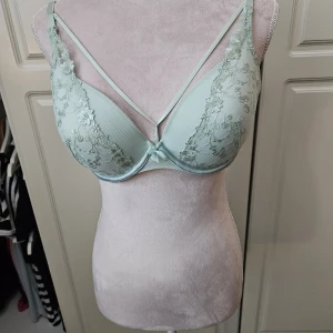 Mintgrön bh Hunkemöller 75D - Vadderad Mintgrön bh med broderade blommor och axelband framtill som är avtagbara . Justerbara axelband och knäppning baktill. Använd 2 ggr. Tyvärr är lappen bortklippt . Nypris 599 kr