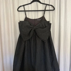 Svart miniklänning - Svart miniklänning från Sister Jane. Den är i jacquard tyg med en stor rosett över bysten och är puffig. Super söt och klassisk!😊❤️