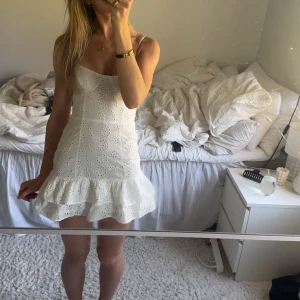 Vit broderad kort klänning med volang - Söt vit klänning med broderade blommor och volang nertill. Perfekt till skolavslutning eller student. Aldrig använd då den är för liten💞