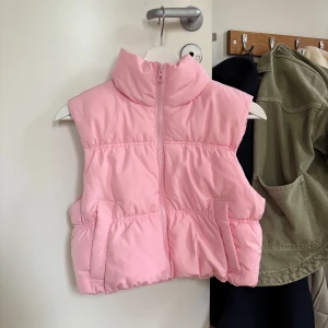 Ljusrosa dunväst med dragkedja - Ljusrosa dunväst med hög krage, dragkedja och fickor. Nypris: 199kr. Aldrig använd, ny med prislapp. Storlek XXS men passar mig som vanligtvis har S i tröjor.🩷