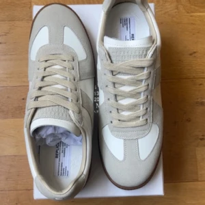 Maison Margiela gats  - Maison Margiela gats i beige mocka och vitt skinn med klassisk gummisula. Perfekta för dig som gillar stilrena och tidlösa sneakers med lyxig känsla och letar efter något nytt inför sommaren. Pris kan diskuteras vid snabb affär 