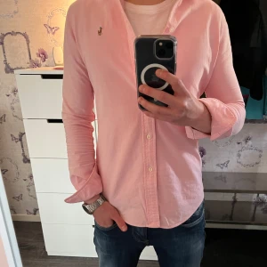 Ralph Lauren Skjorta - Ny - Säljer en jättefräsch Ralph lauren skjorta i storlek XS och färgen rosa då jag föredrar en storlek större på mig! Helt nytt skick - 10/10, inte ens använd - endast testad. För referens är jag på bilden 171 och väger 57 kg. Skjortan har en slim passform. Vid minsta lilla fråga hör av er!