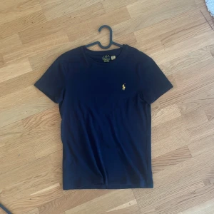 Svart t-shirt från Polo Ralph Lauren - Säljer en svart t-shirt från Polo Ralph Lauren med korta ärmar. Tröjan är i bra skick. Pris kan diskuteras. 