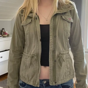 Hollister jacka - Skit snygg vår/sommarjacka från hollister. Den är i en khaki grön färg och har åtdragningsbara band vid midjan. Storlek M men sitter mer som S/XS. Priser är diskuterbart 