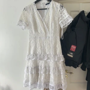 Student klänning - Student klänning i spets och volanger. Från French Connection. Köptes för 1000kr secondhand, säljer då den tyvärr är lite stor i bysten. Storlek XS, längd = 91cm, bredd (armhålorna)= 46cm. Bra skick. Vit/benvit/naturvit,( inte helt ”kritvit”)Skriv för fler frågor 🩷