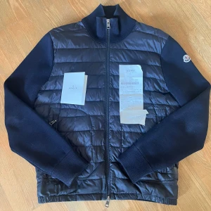 Moncler cardigan - En marinblå Moncler cardigan i storlek S i rätt bra skick. Lite smutsig på framsidan på dunet samt små hål vid ärmarna som visas på bild. Kvitto medföljer vid köp