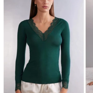 Mörkgrön långärmad topp med spetsdetaljer - Snygg mörkgrön långärmad topp med v-ringning och spetsdetaljer vid halsringning och ärmslut. Figurnära passform som passar perfekt till både jeans och kjol. Mjuk och bekväm att bära. pris kan diskuteras 🫶
