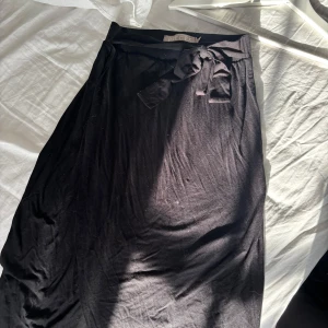 Svart omlottkjol med knyt  - Svart omlottkjol från Pieces med knytband i midjan. Kjolen har en enkel och stilren design som passar perfekt till många olika looks. Mjuk och lätt i materialet, midilängd🩷nypris 399 