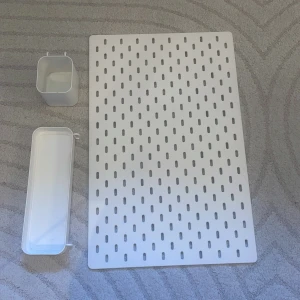 Vit perforerad förvaringspanel med tillbehör - Säljer en vit perforerad förvaringspanel med två tillhörande behållare, perfekt för att organisera småsaker. Panelen har ett modernt och stilrent utseende och är tillverkad i tålig plast. Passar bra i både sovrum och kontor för smart förvaring.