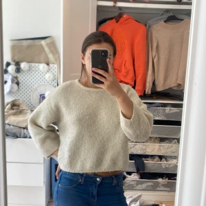 Beige stickad tröja - Säljer en enkel och stilren beige stickad tröja med rund halsringning. Tröjan har en croppad passform och långa ärmar, perfekt att matcha med jeans eller kjol.