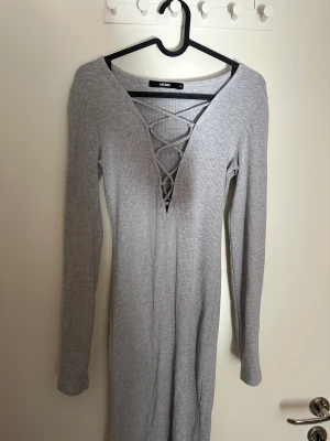 Klänning BikBok - En grå klänning från BikBok. Har ett pyttelitet hål vid urringningen, men inget som märks när man har den på. Går att ha som både lårkort klänning eller ner till knäna