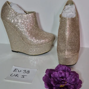 Partyklackar guld glitter strl 38 - Supersnygga kilklackari guld glitter Supersvårt att fånga deras fulla glittrighet på bild =/  Klackhöjd ca 15 cm Platå ca 5 cm  Skorna är nya och oanvända men har fläckar, lim som blivit gult syns mer på bild än i verkligheten.