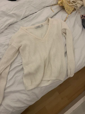 Vit stickad mjuk - Vit sticksd med v-ringad öppning 