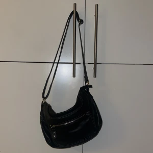 Väska - Väska med ställbart band och med silvriga detaljer. Mycket bra med fack både på insidan och utsidan. I mycket gott skick 