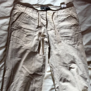 Khaki byxor - Khakifärgade lite vida byxor som går att knäppa upp där nere om man vill att de ska vara lite lärngre.