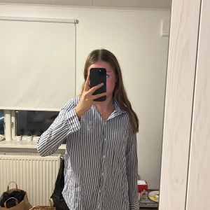 Blå och vitrandig skjorta - Snygg blå och vitrandig skjorta som är jättefin och somrig att bara ha som den är eller över en annan tröja. Bra skick men kommer tyvärr inte till användning. Även liten i storleken. 