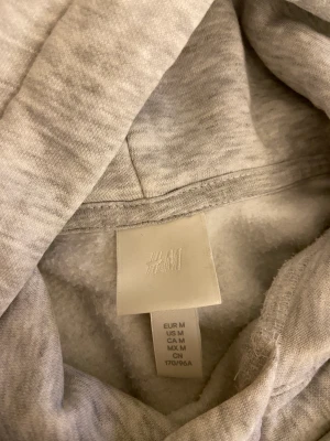 Grå hoodie  - En fin hoodie men grön text där fram från H&M 
