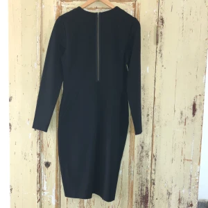Klänning, svart med detaljer - Svart, ny klänning, från Wera, nypris 599:-Längd 102 cm 68% vikos, 29% polyamid, 5% elastan. Detaljer med dragkedja (färg mässings) fram och i rygg.